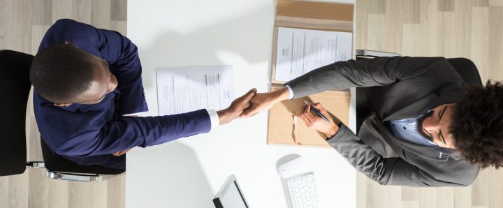 Businessmen shaking hands after signing legal paperwork to open a courier business