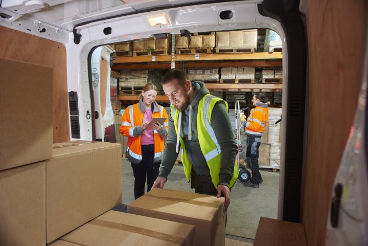 Warehouse order-pickers loading packages in a delivery car