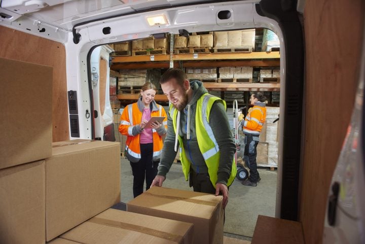 Warehouse order-pickers loading packages in a delivery car