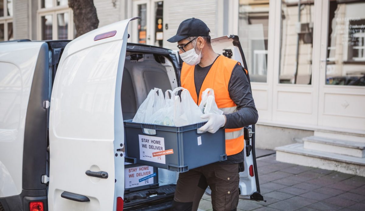 Delivery driver loading packages into delivery car for contactless delivery during the COVID-19 pandemic 