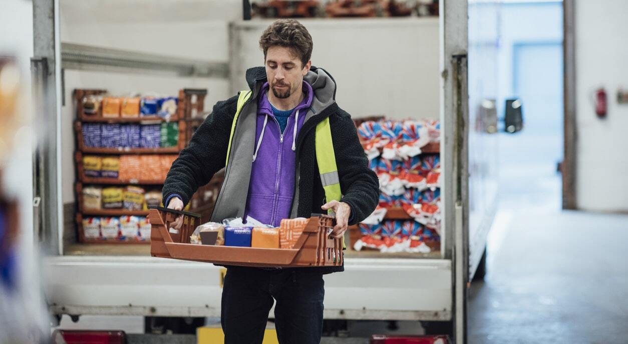 Food delivery services with delivery driver unloading fresh produce from a van.